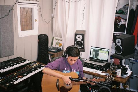 a woman recording an acoustic guitar in a home studio