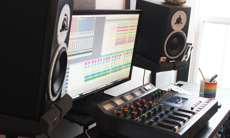 Home studio set up with mixing console, monitor, and speakers on either side