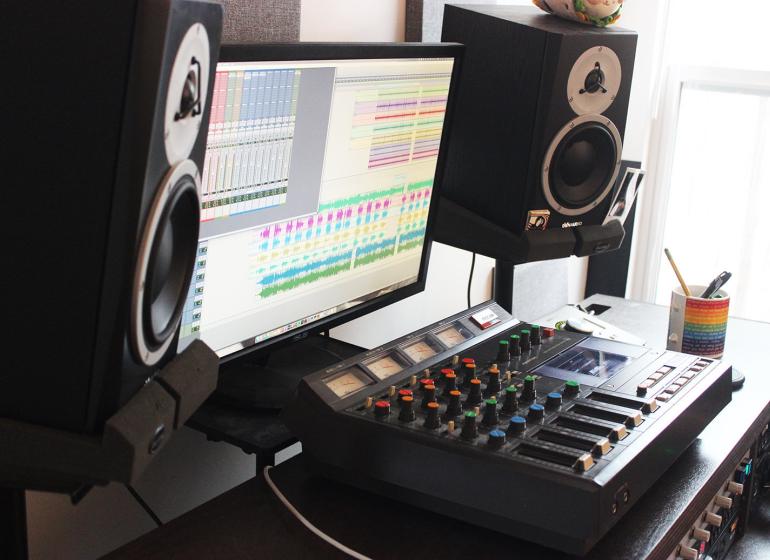 Home studio set up with mixing console, monitor, and speakers on either side