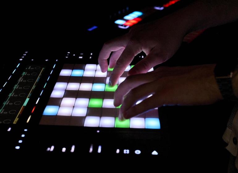 Close up of hands using a digital sampler in a studio environment