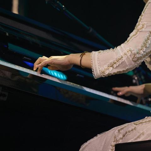 A woman playing a grand piano on stage