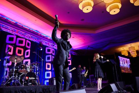 Performers on stage in a dramatically lit room at the Amplify Gala