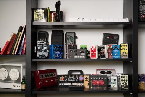 A floor to ceiling shelf filled with Suzy Shinn's various guitar effects pedals