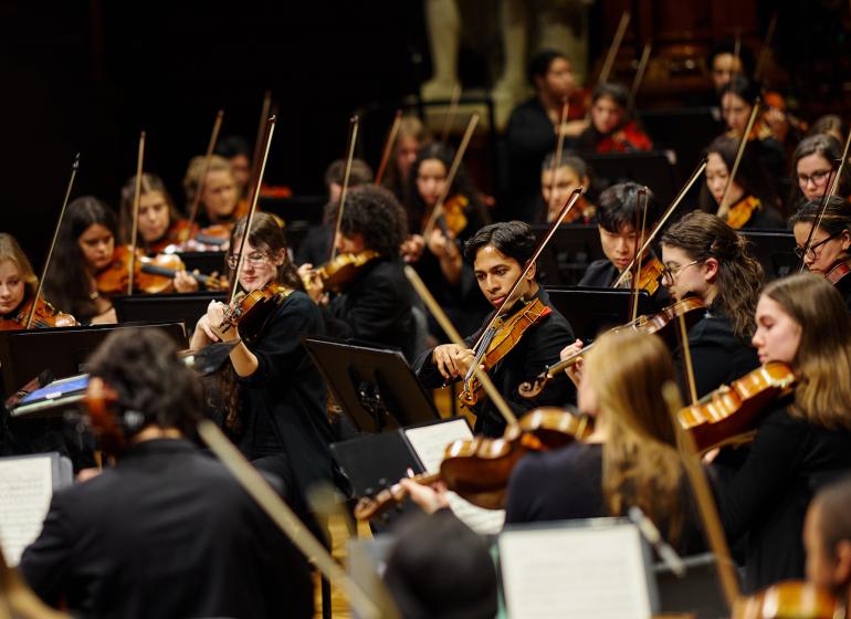 Boston Conservatory Orchestra strings students performing in concert black on stage.