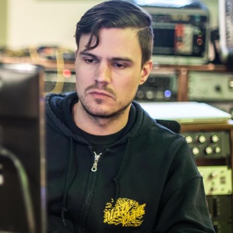 Benny Grotty sitting and looking at a computer surrounded by recording gear