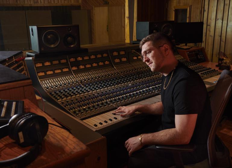 Charlie Rosen '12 behind a mixing board in a studio