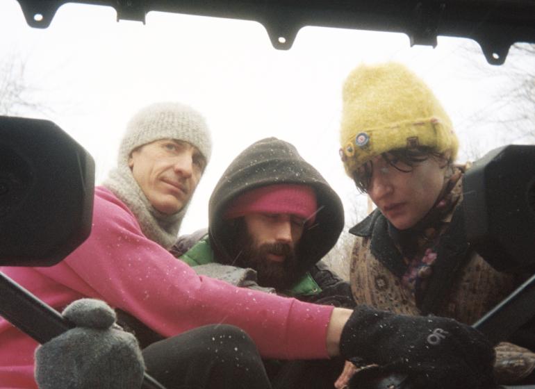 three band members in winter clothes on a snowy day