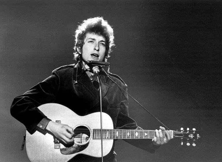 Black and white image of a young Bob Dylan performing onstage