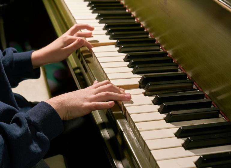 closeup of child's hands playing a piano