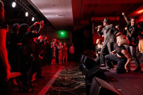 Students performing on stage at Amplify Berklee while attendees of the annual gala gather around the stage to watch.