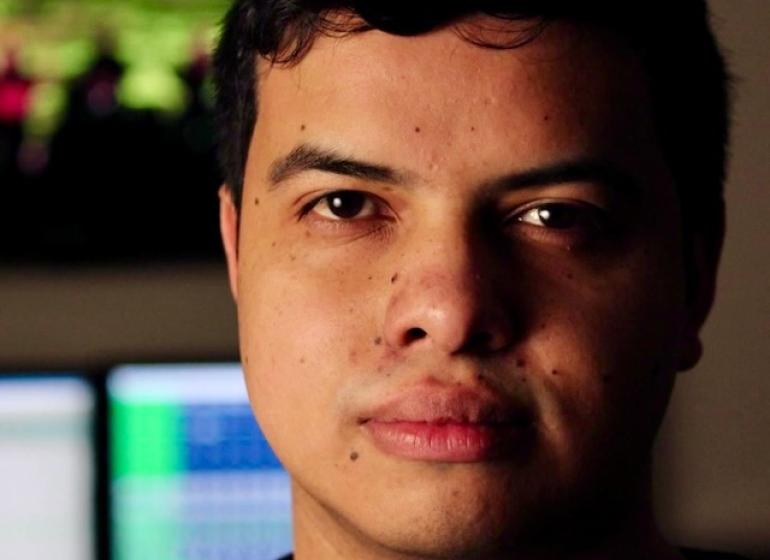 Headshot of Mateo Londoño with a music production setup in the background