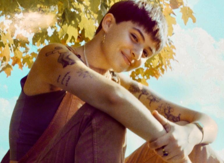 Indigo Ansin sits on a rock under a tree