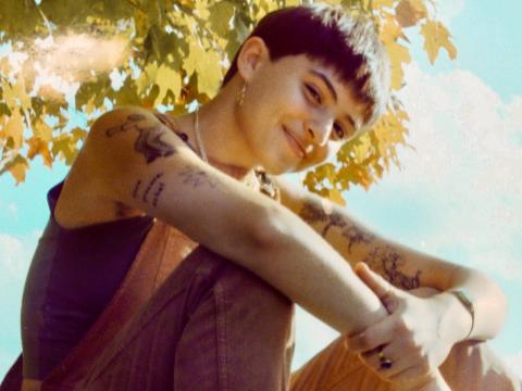 Indigo Ansin sits on a rock under a tree