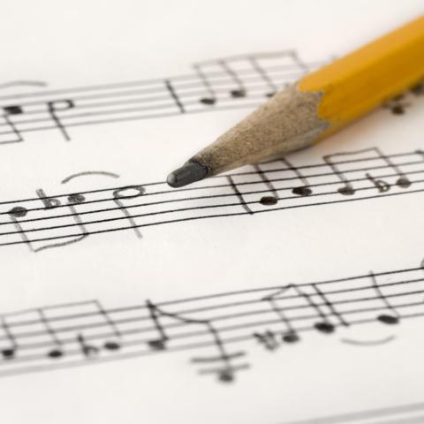 A yellow pencil on top of written sheet music.