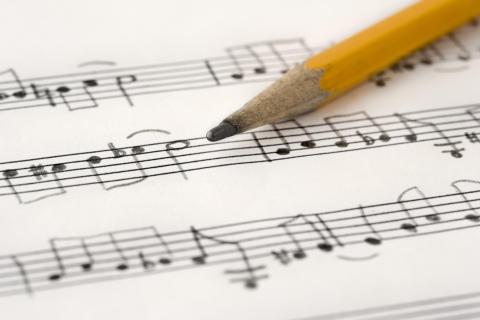 A yellow pencil on top of written sheet music.