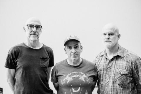 Three men against a grey backdrop, black and white photo