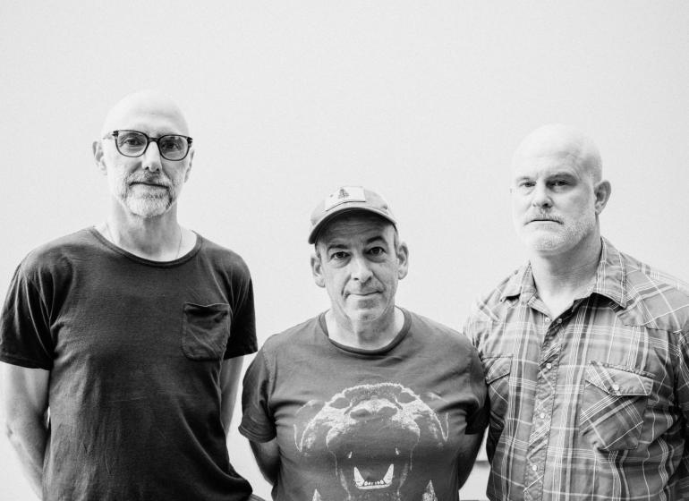 Three men against a grey backdrop, black and white photo