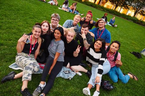 Students gathering and smiling sitting on the lawn