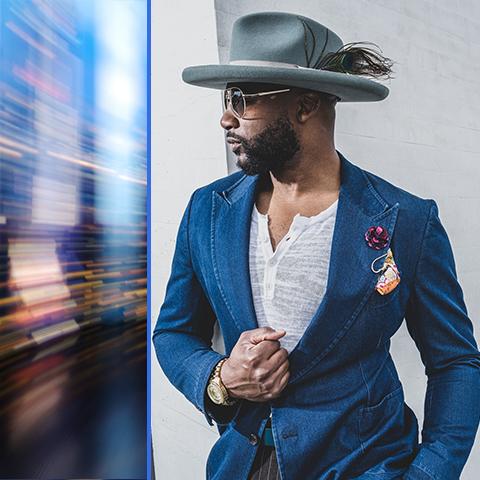 Norman Garrett headshot, in blue suit and hat, looking to the left