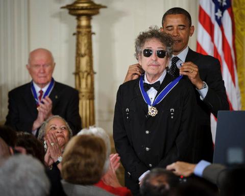 President Barack Obama standing behind Bob Dylan and bestowing upon him the Presidential Medal of Freedom