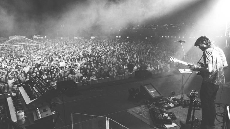 black and white photo of a guitarist playing at night in front of an outdoor concert audience