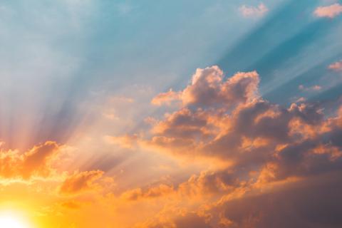 The sun is rising in the lower left corner of the screen, and the sky is filled with orange and pink clouds.