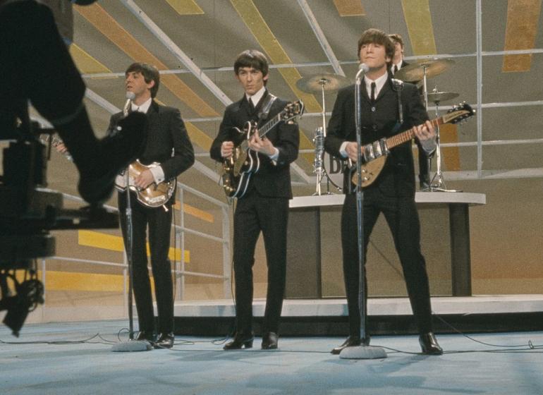 The Beatles performing on the stage of the 'Ed Sullivan Show' in 1964