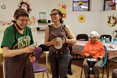 A Music therapist playing percussion with two senior adults