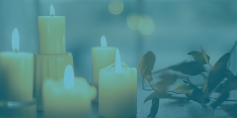 Candles sit on a table with greenery